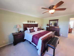 Carpeted bedroom featuring ornamental molding and ceiling fan