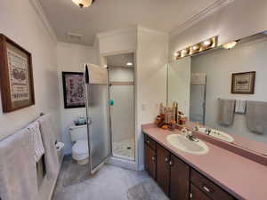 Bathroom with crown molding, vanity, toilet, and a shower with door