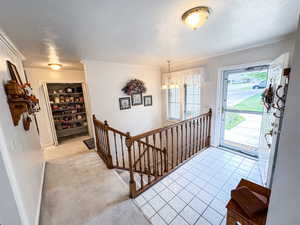 Entrance foyer featuring light colored carpet, a chandelier, crown molding, and a textured ceiling