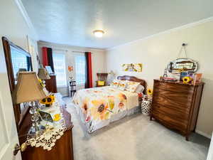 Bedroom with a textured ceiling, crown molding, and carpet floors