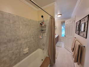 Bathroom with vanity, ornamental molding, and shower / bathtub combination with curtain