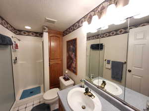 Bathroom with a textured ceiling, vanity, walk in shower, toilet, and tile patterned floors