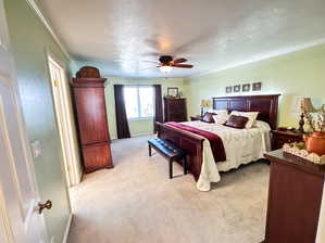 Bedroom featuring ceiling fan, crown molding, and light carpet