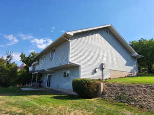 View of side of property featuring a balcony, a yard, and a patio