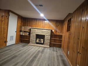 Unfurnished living room with wood walls, a fireplace, and dark wood-type flooring