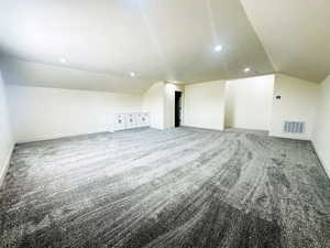 Additional living space featuring carpet floors, a textured ceiling, and vaulted ceiling