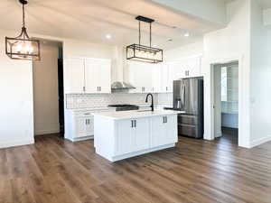 Kitchen featuring dark hardwood / wood-style flooring, decorative light fixtures, stainless steel appliances, and white cabinets