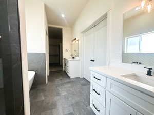 Bathroom featuring vanity, a bathing tub, tile walls, and a chandelier