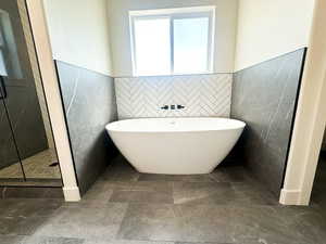 Bathroom featuring plus walk in shower and tile walls