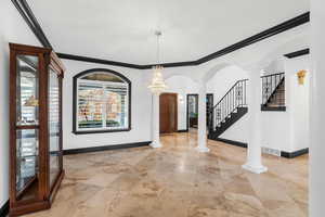 Foyer featuring a chandelier, ornate columns, and ornamental molding