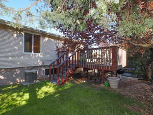 Rear view of property featuring central AC, a wooden deck, and a yard