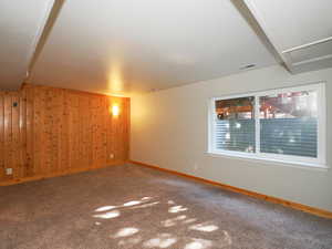 Carpeted empty room featuring wood walls