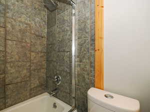 Bathroom with toilet and tiled shower / bath combo