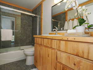 Full bathroom with shower / bath combination with glass door, tile patterned flooring, toilet, and vanity