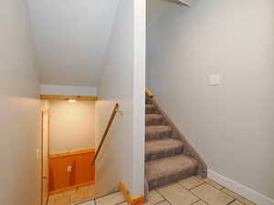 Stairs featuring lofted ceiling and tile patterned floors