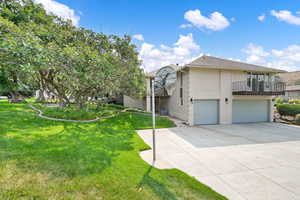 View of front of property with a garage, a front lawn, a balcony, and central air condition unit