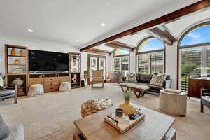 Carpeted living room with a textured ceiling and beamed ceiling