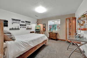 Bedroom with a textured ceiling and carpet