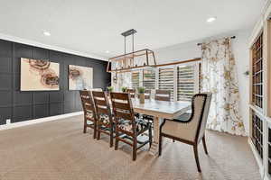 Dining room featuring a textured ceiling, light carpet, and ornamental molding