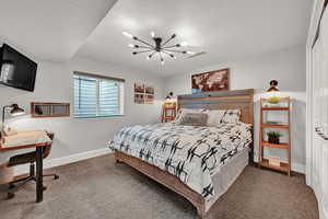 Bedroom with a closet, an inviting chandelier, carpet, and a textured ceiling