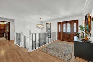 Foyer featuring ornamental molding, a chandelier, and light hardwood / wood-style floors