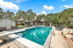 View of pool with a storage unit, a diving board, and a patio