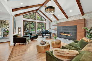 Living room with light hardwood / wood-style floors, high vaulted ceiling, beam ceiling, and a tile fireplace