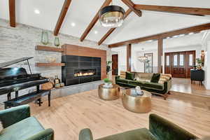 Living room with light hardwood / wood-style floors, beamed ceiling, a chandelier, and a tile fireplace