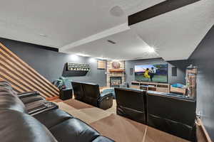 Carpeted home theater featuring a textured ceiling and a fireplace