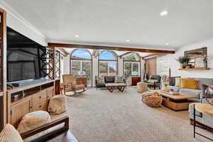 Living room featuring a textured ceiling, carpet, and ornamental molding