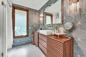 Bathroom featuring crown molding, vanity, and tile walls