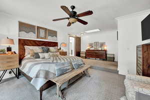 Carpeted bedroom featuring ceiling fan and crown molding