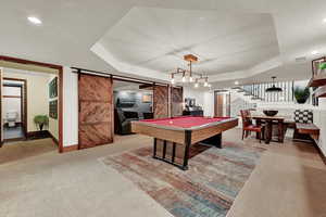 Playroom featuring pool table, a barn door, carpet flooring, a raised ceiling, and a textured ceiling