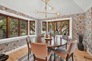 Dining area with crown molding, lofted ceiling, a notable chandelier, and light hardwood / wood-style floors