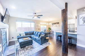 Living room with ceiling fan with notable chandelier, dark hardwood / wood-style flooring, and a textured ceiling