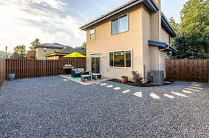 Rear view of house with central AC unit and a patio area.*Fence to be painted by HOA in 2025