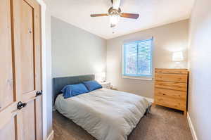 Bedroom featuring a textured ceiling, dark carpet, and ceiling fan