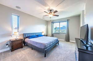 Bedroom with ceiling fan, a textured ceiling, and carpet floors