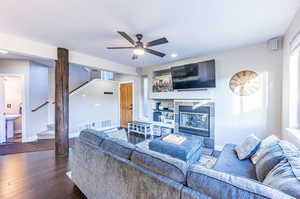 Living room with a fireplace, ceiling fan, and dark hardwood / wood-style floors