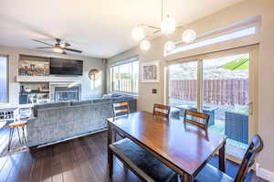 Dining space featuring dark wood-type flooring and ceiling fan with notable chandelier