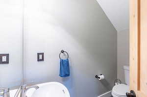 Bathroom featuring vaulted ceiling, sink, and toilet