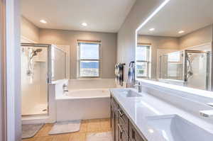 Bathroom featuring tile patterned floors, separate shower and tub, and vanity