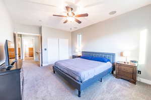 Carpeted bedroom featuring ceiling fan and a closet