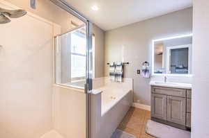 Bathroom with tile patterned flooring, vanity, and shower with separate bathtub