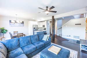 Living room featuring ceiling fan with notable chandelier, dark hardwood / wood-style floors, and sink