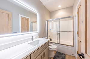 Full bathroom with combined bath / shower with glass door, vanity, toilet, and tile patterned floors