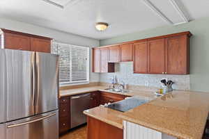 Kitchen with  tasteful backsplash, kitchen peninsula, sink, and light stone counters