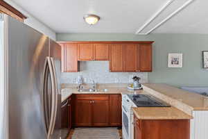 Kitchen with tile patterned flooring, backsplash, kitchen peninsula, and sink