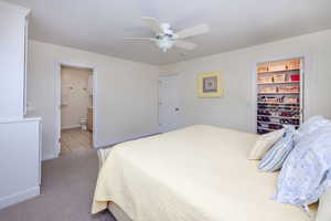 Carpeted bedroom with connected bathroom, a walk in closet, ceiling fan, and a closet