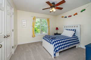 Carpeted bedroom featuring ceiling fan